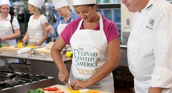 A woman in a Culinary Institute of America apron chops vegetables in a bustling kitchen. As other students work diligently nearby, under the watchful eye of a chef in a white coat, one cant help but imagine the culinary travel packages that inspire such scenes of culinary passion and skill. A woman in a Culinary Institute of America apron chops vegetables in a bustling kitchen. As other students work diligently nearby, under the watchful eye of a chef in a white coat, one cant help but imagine the culinary travel packages that inspire such scenes of culinary passion and skill.