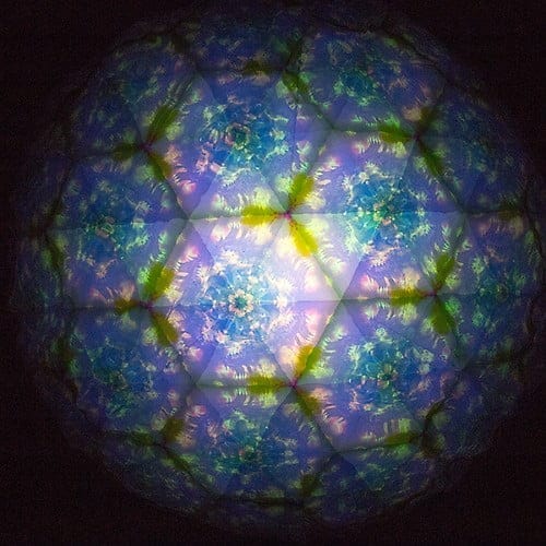 A kaleidoscope image conjures the tranquility of a Catskills Resort & Spa, featuring a spherical pattern of vibrant blue, green, and yellow hues. The intricate design consists of symmetrical, geometric shapes and floral-like patterns, creating a mesmerizing visual effect.