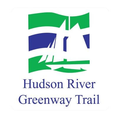 Logo of the Hudson River Greenway Trail, part of the Empire State Trail, featuring stylized green and blue waves with a white sailboat silhouette in the middle. The text Hudson River Greenway Trail is below the image.