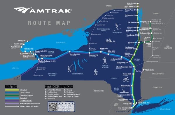 Map showing Amtrak routes and stations in New York by Rail. It highlights cities like Albany, Syracuse, and Buffalo, with routes extending to nearby states and Canada. Icons indicate services like Wi-Fi and baggage. Lakes Erie and Ontario are visible.